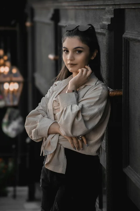 A woman leaning against a wall with her hand on her chin