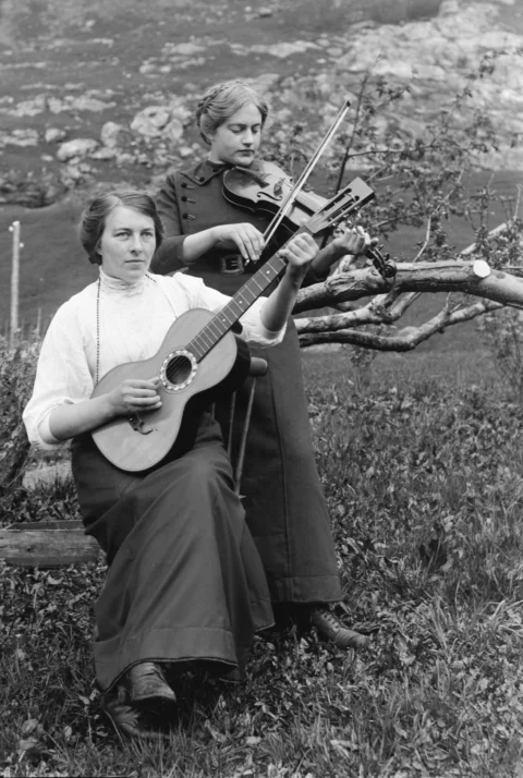 Two women playing guitar and violin outdoors