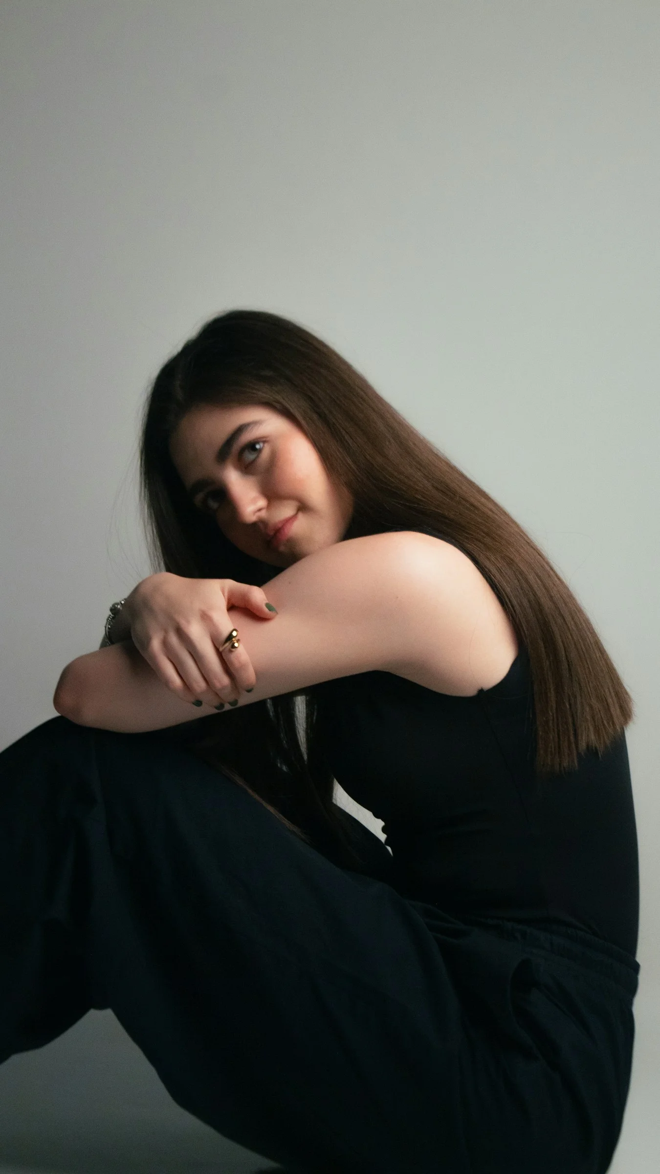 Young woman in black sitting, looking at the camera