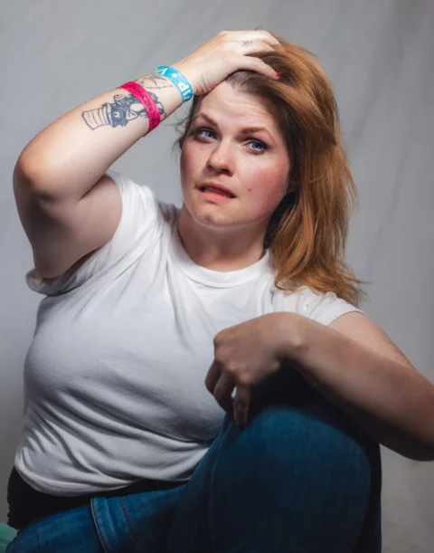 A woman sitting on a chair with a tattoo on her arm