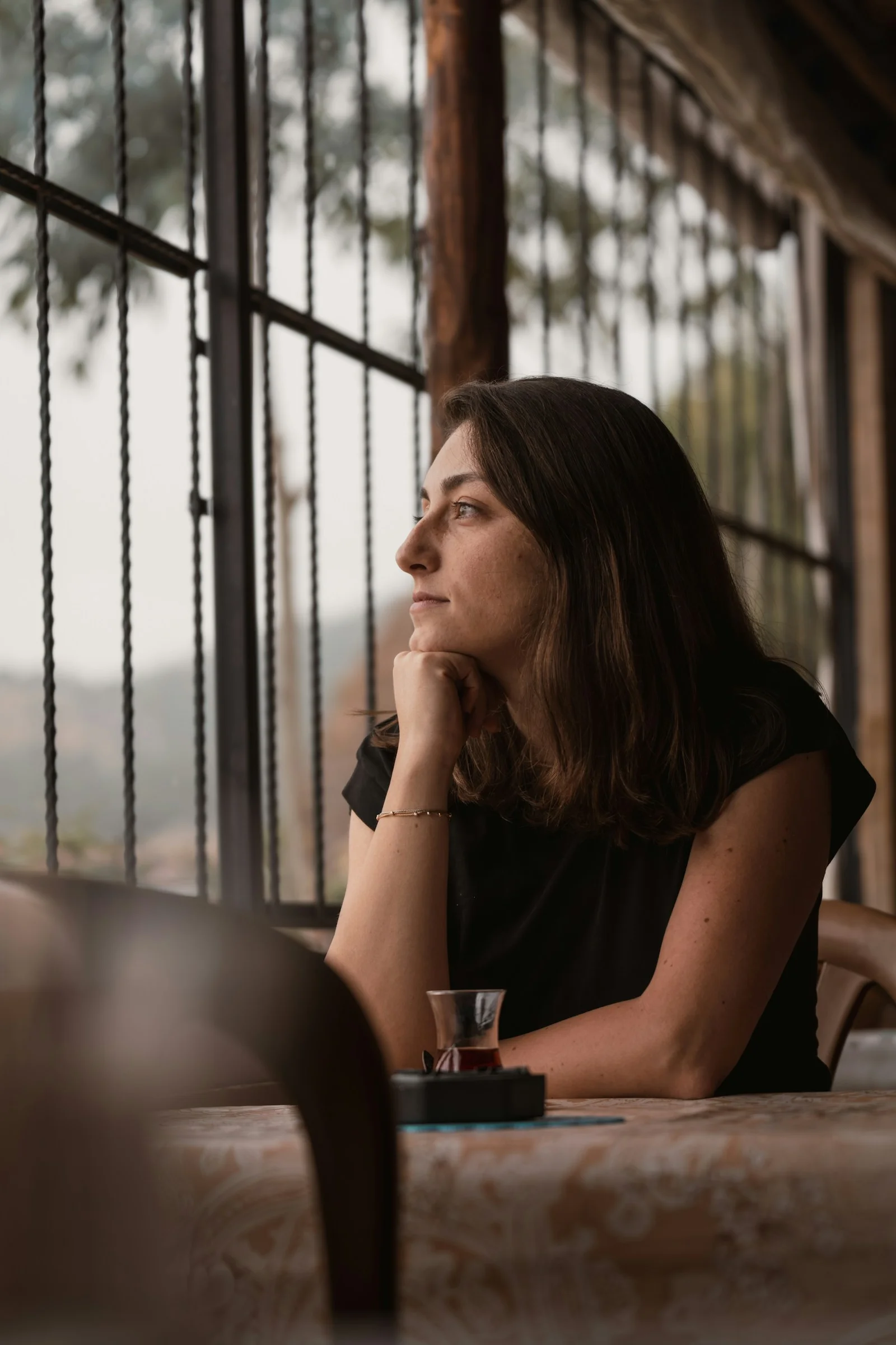 A woman sitting at a table with her hand on her chin