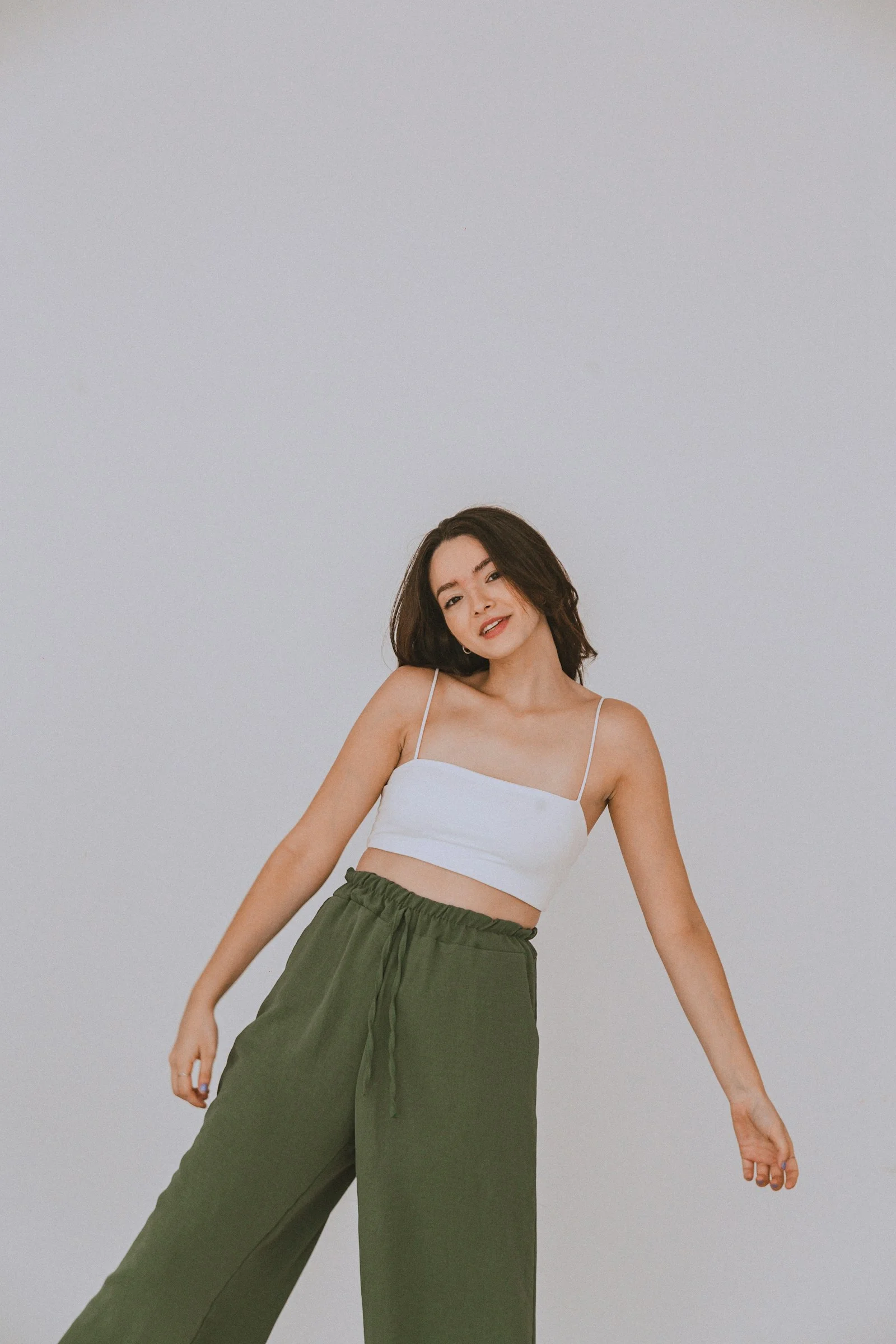 a woman in a white top and green pants