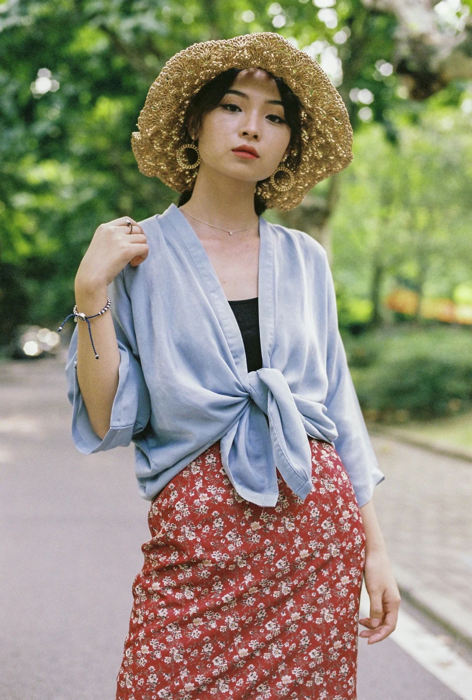 青いカーディガンと赤いスカートを着て立っている女性