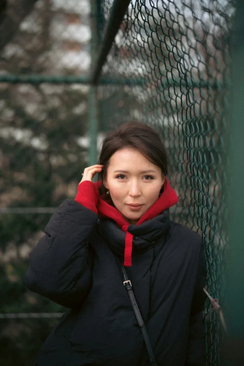 一位身穿黑色夹克倚靠在栅栏上的女子