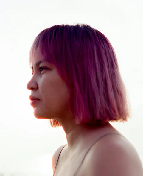 ピンクの髪の女性が遠くを見つめている