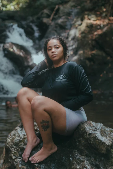 a woman sitting on a rock in front of a waterfall