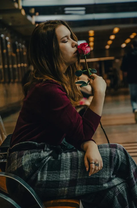 一个女人坐在长椅上，嘴里含着一朵花