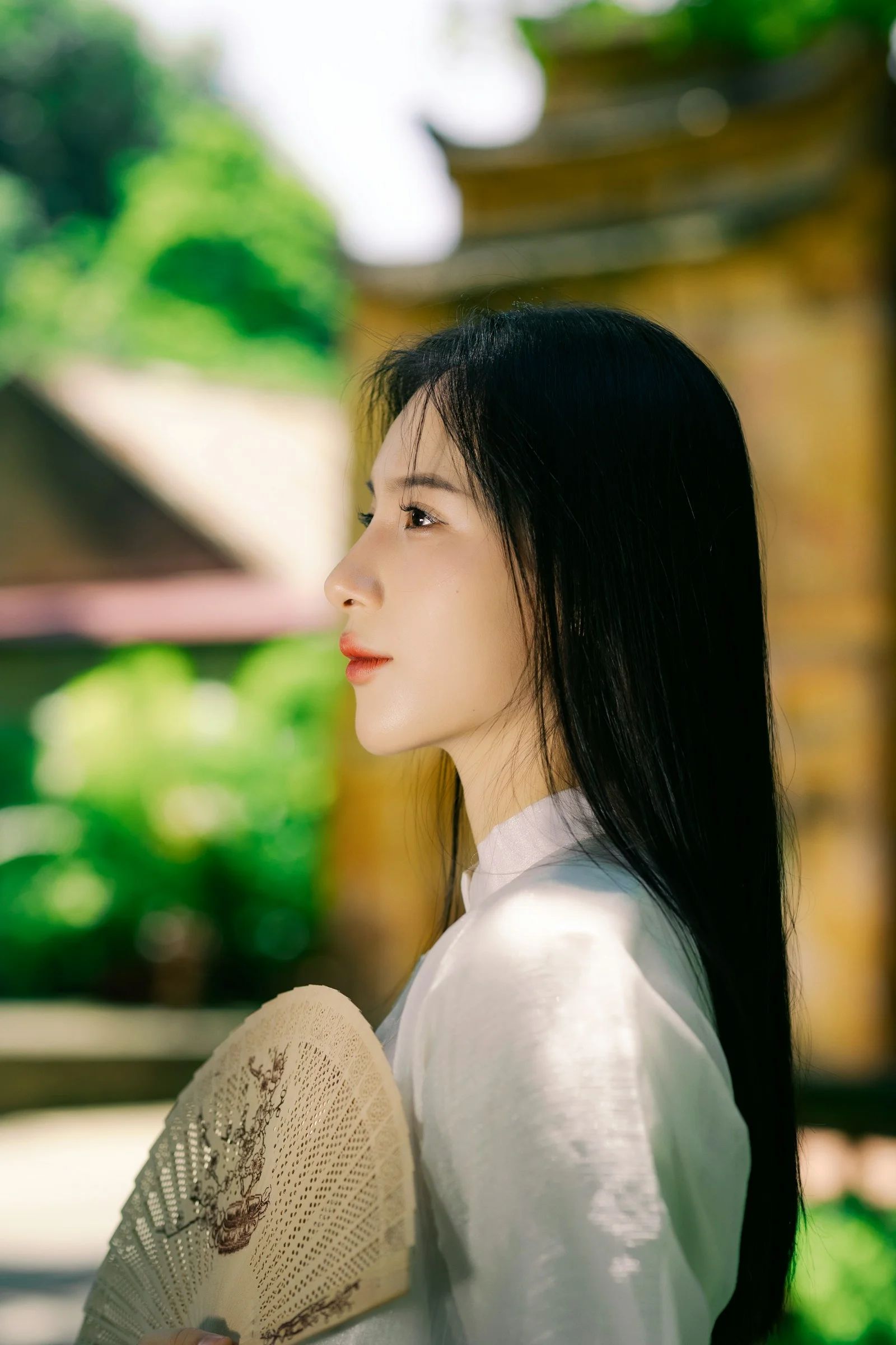 A woman in a white dress holding a fan