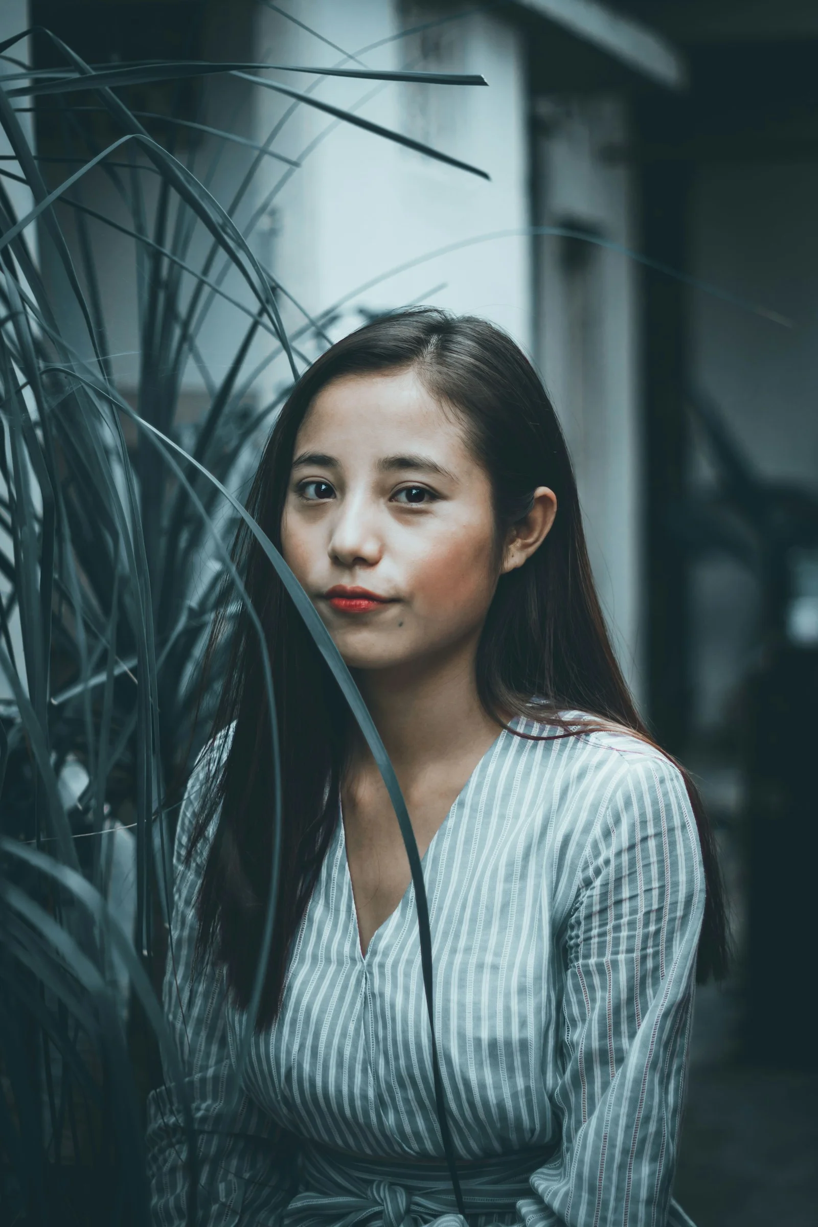 身穿黑白条纹衬衫的女性站在绿色植物旁