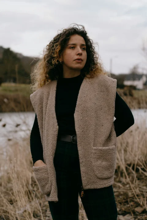 woman in brown coat standing on field during daytime