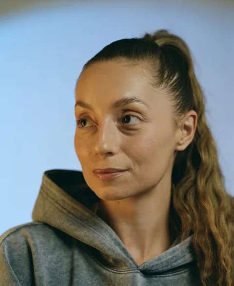 A woman with a ponytail wearing a grey hoodie