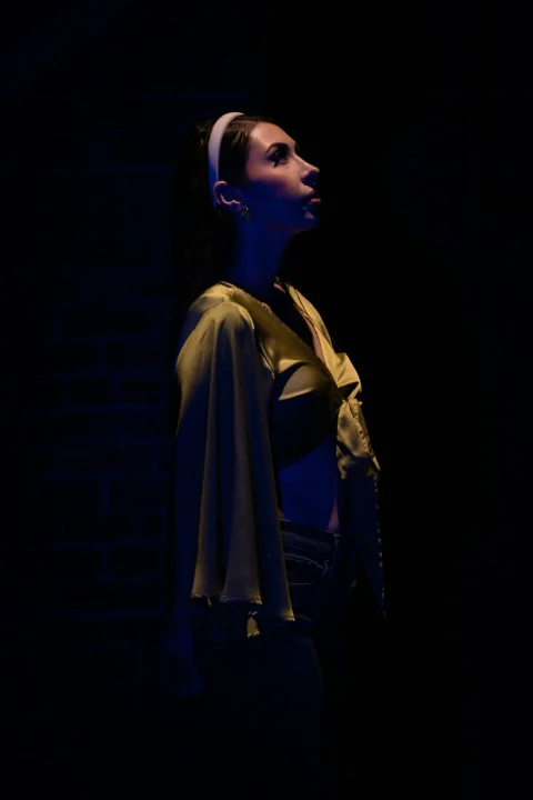 a woman standing in the dark wearing a cape