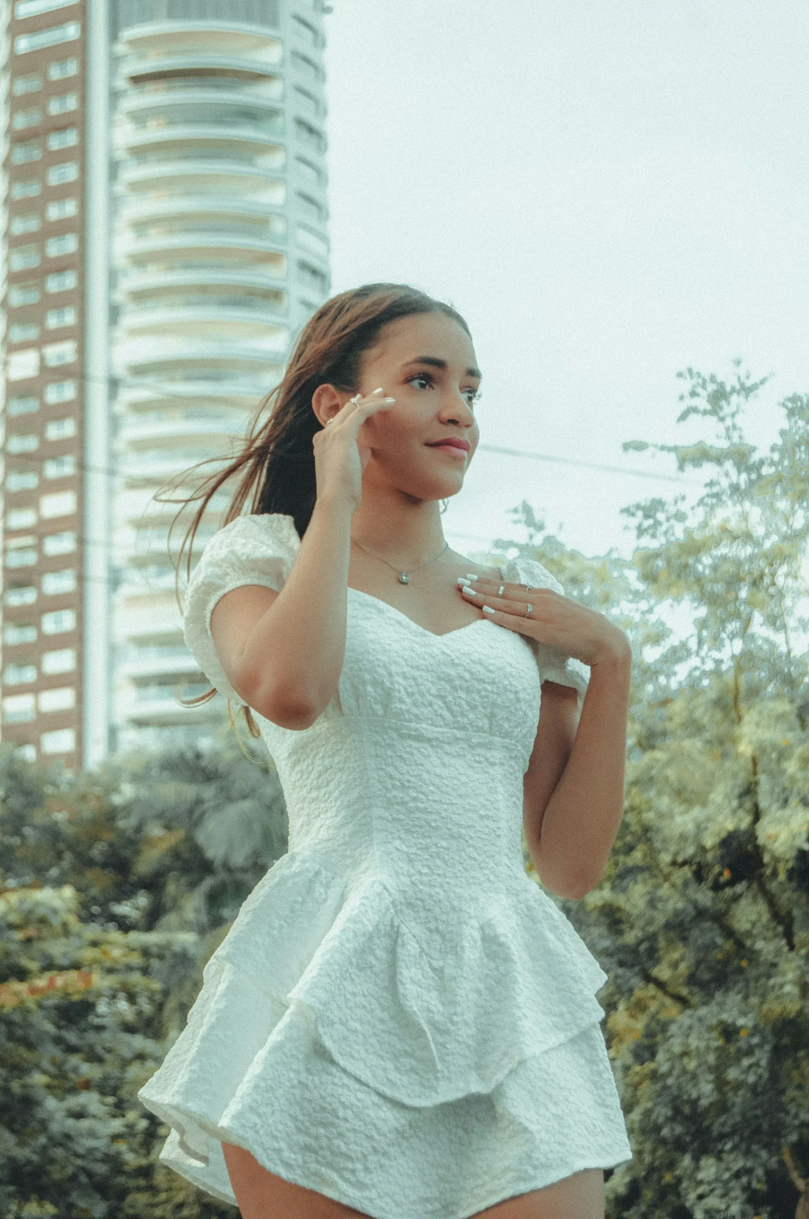 a woman in a short white dress standing in front of a tall building