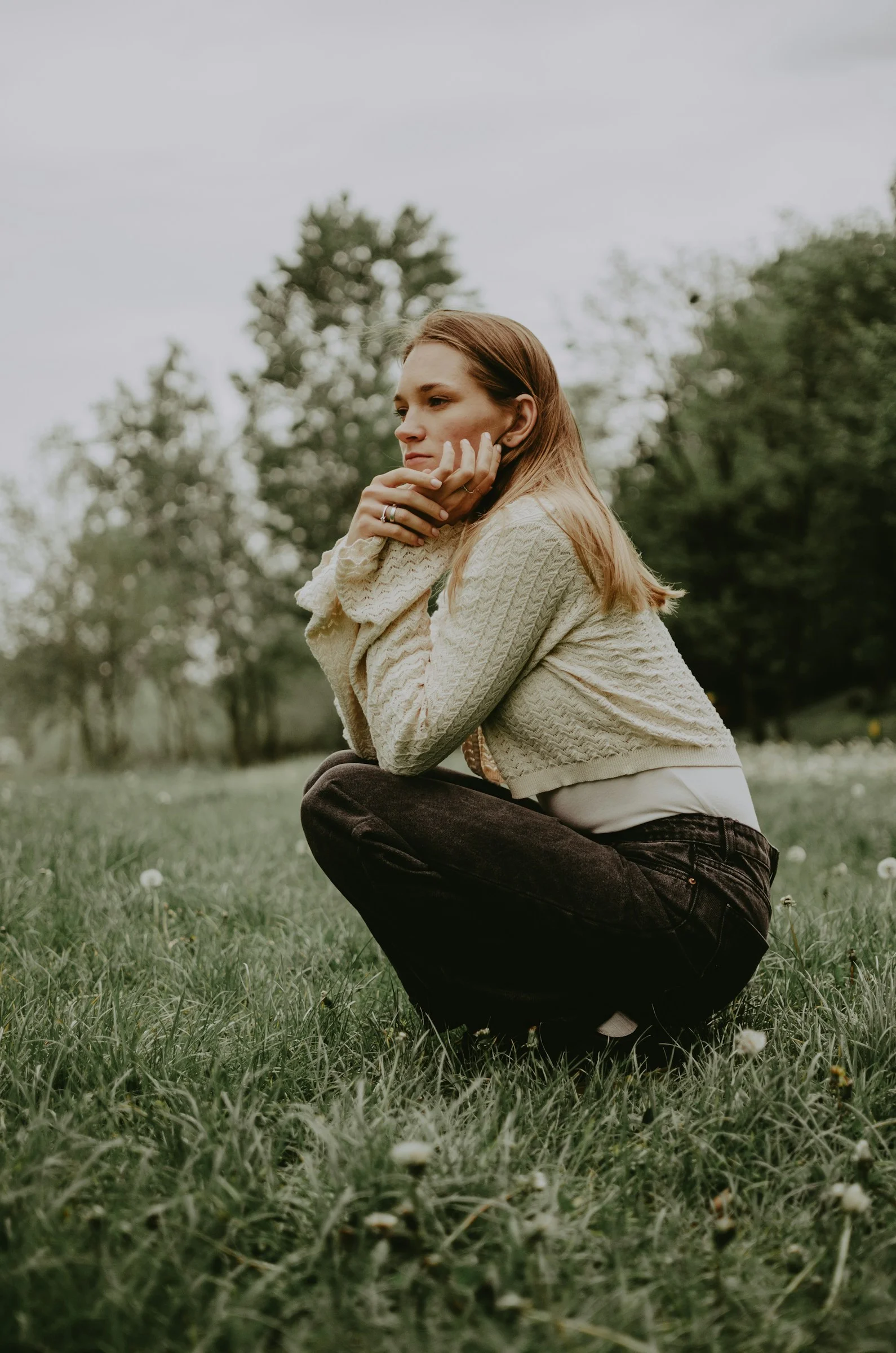 A woman squats in a grassy field