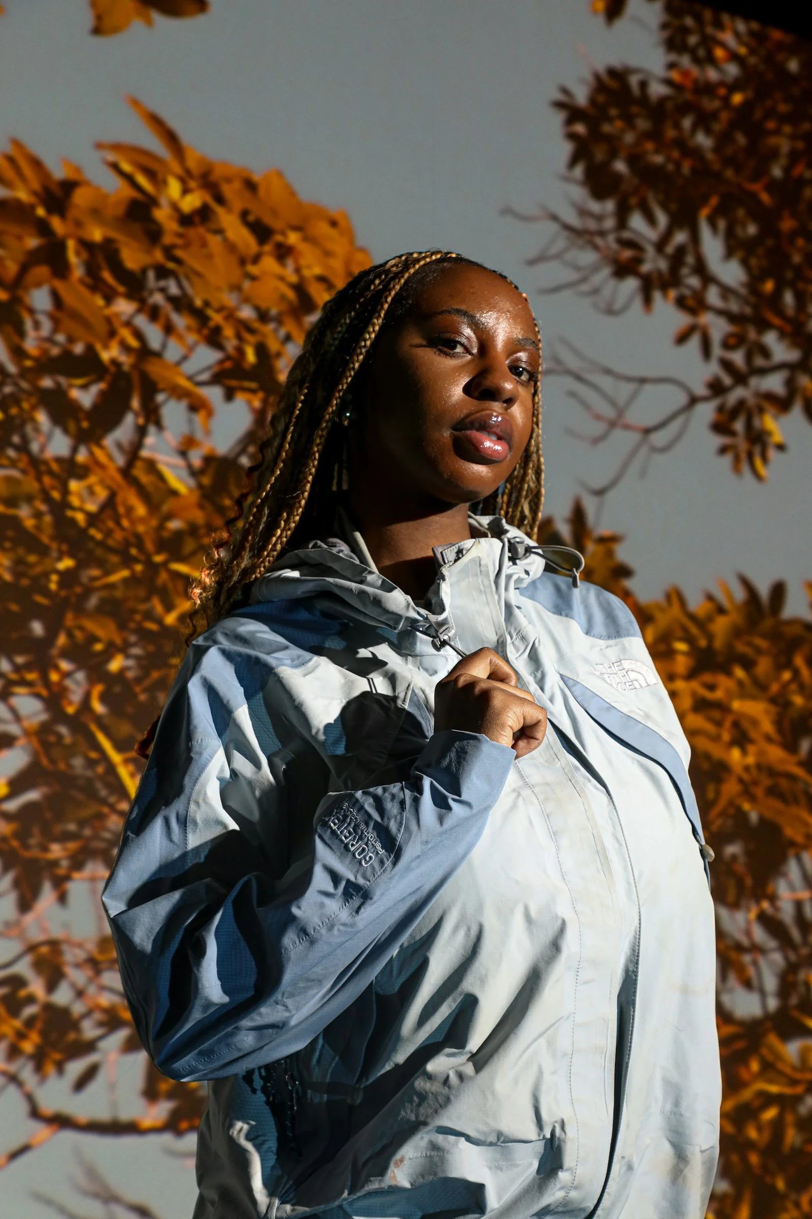 a woman with dreadlocks standing in front of a tree