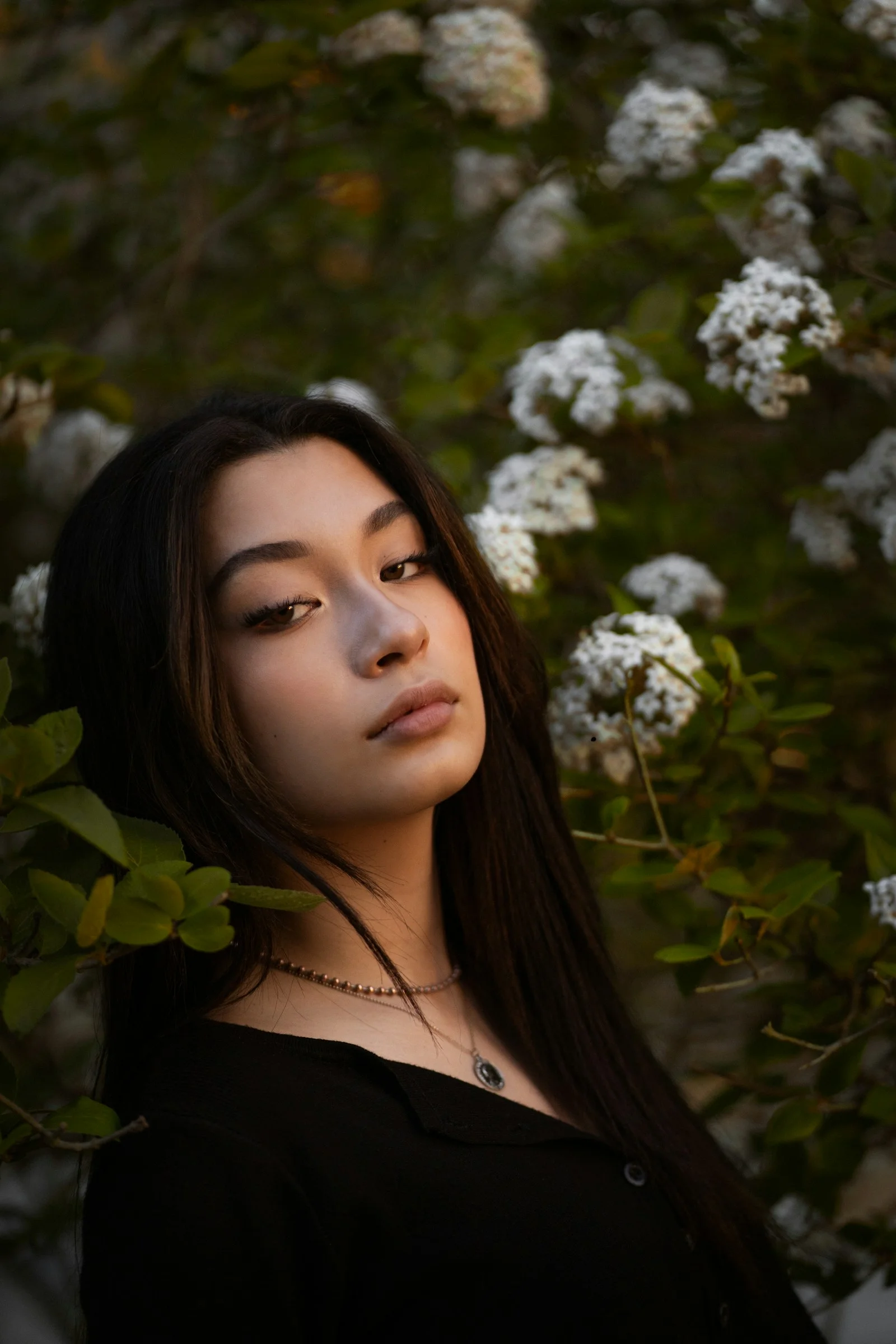 穿黑色襯衫的女人站在白花下