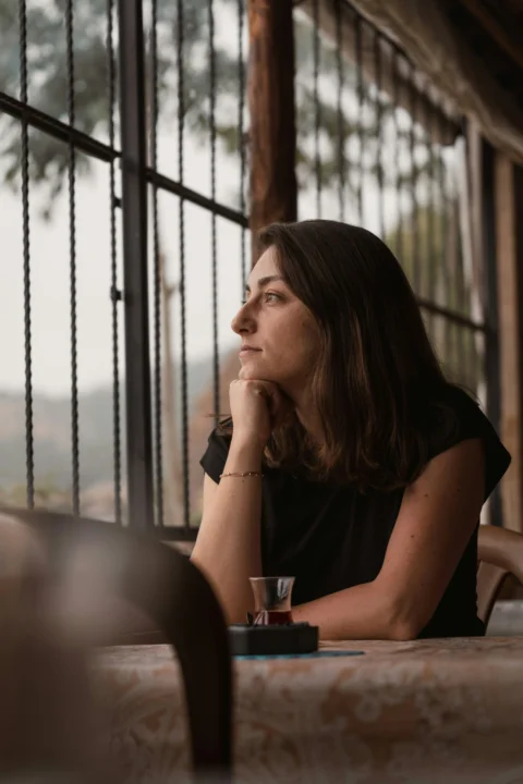 A woman sitting at a table with her hand on her chin