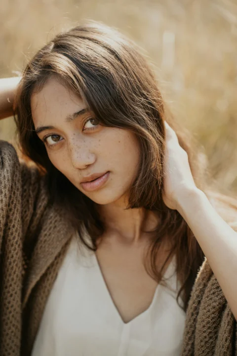 A woman is posing for a picture in a field