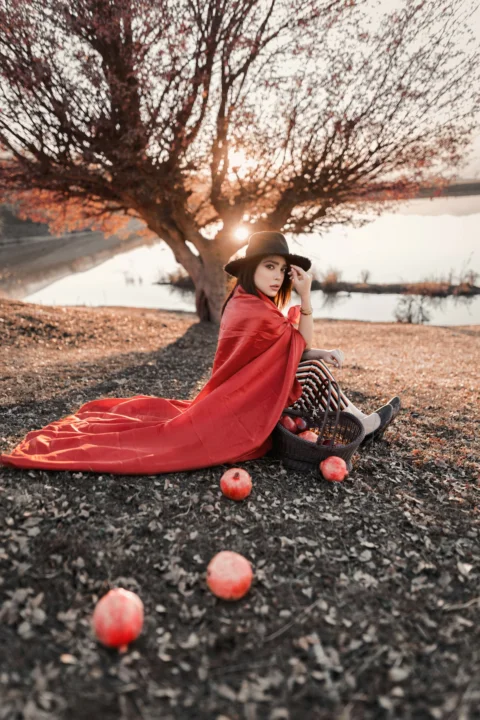 女子坐在一篮苹果旁，地上还放着苹果
