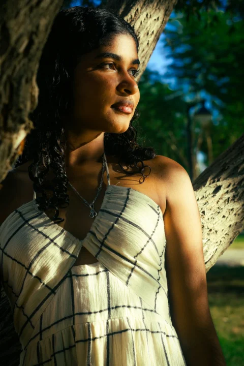 Young woman in a checkered dress by a tree