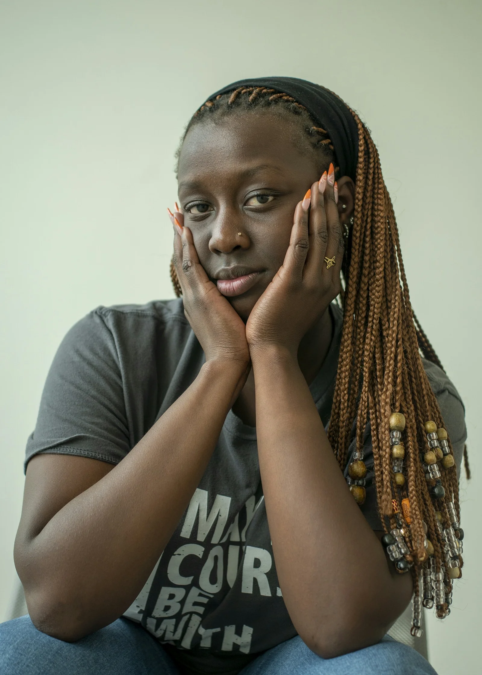 A woman with braids gazes thoughtfully at the camera