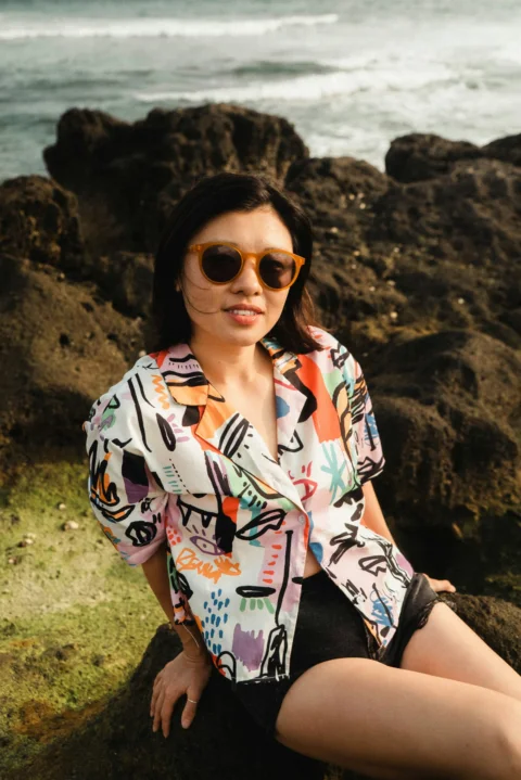 a woman sitting on a rock next to the ocean