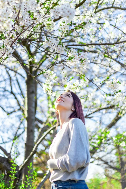 一个女人站在开满白花的树前
