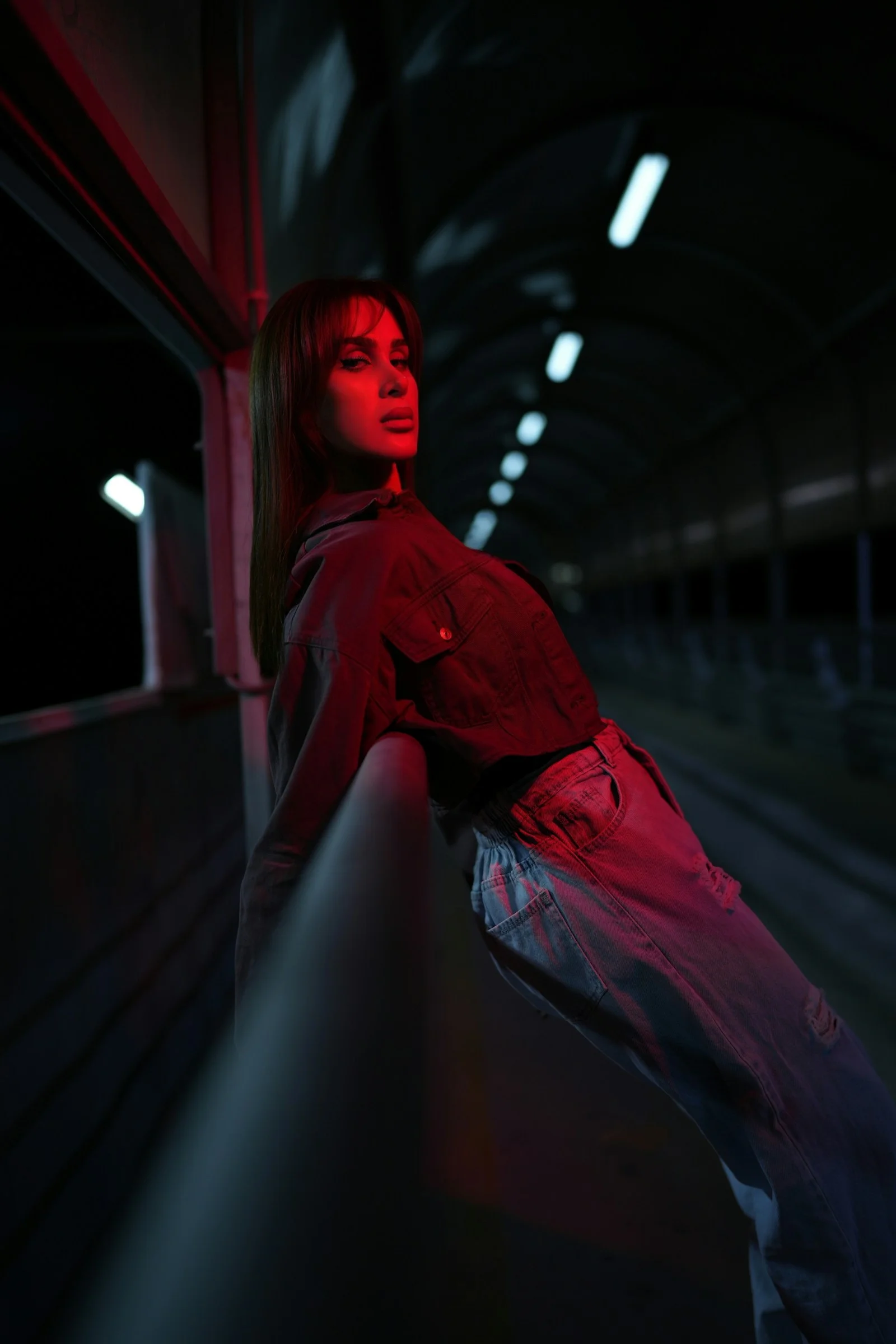 A woman leaning on a railing under red light at night