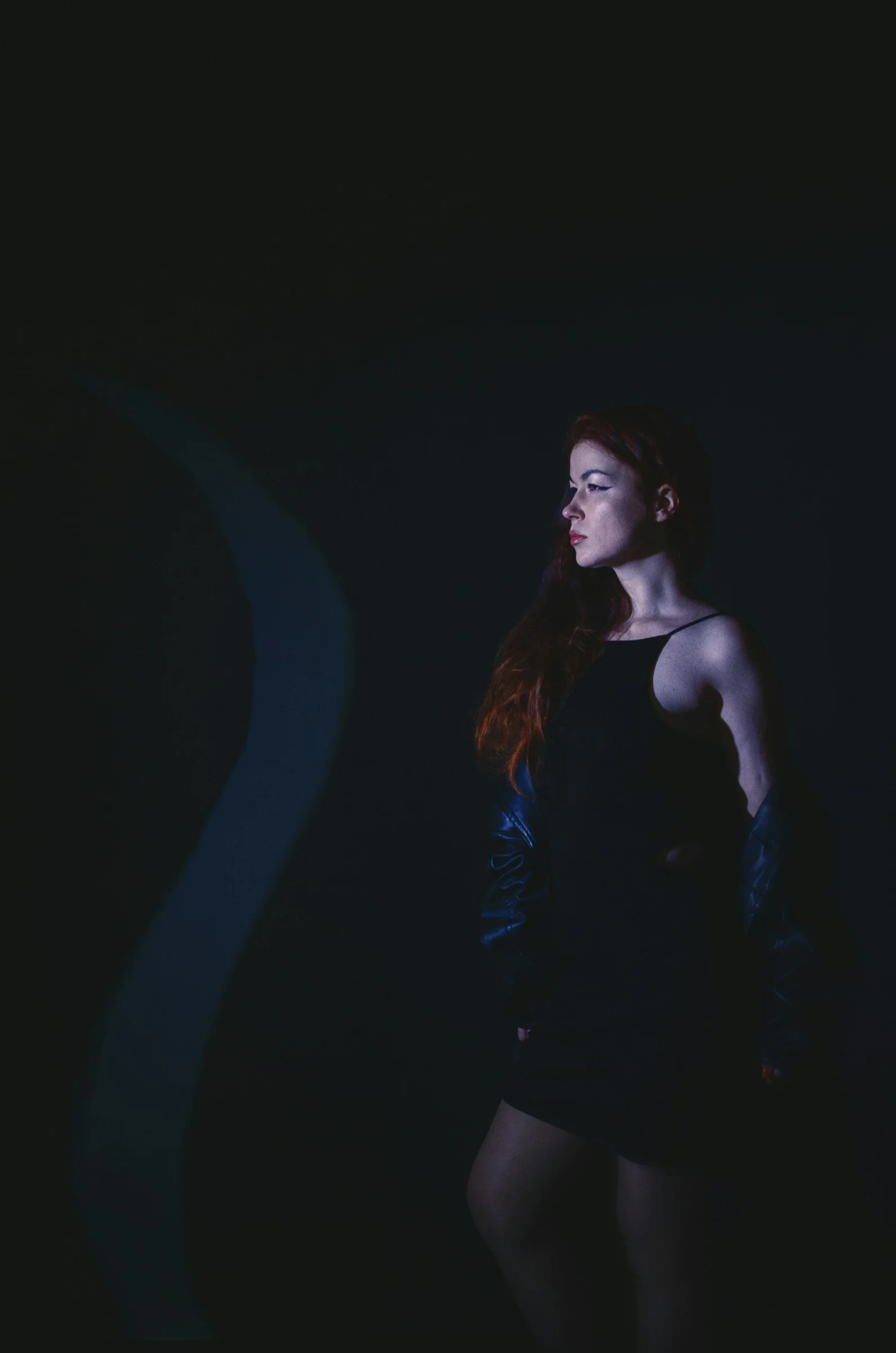 a woman in a black dress standing in the dark