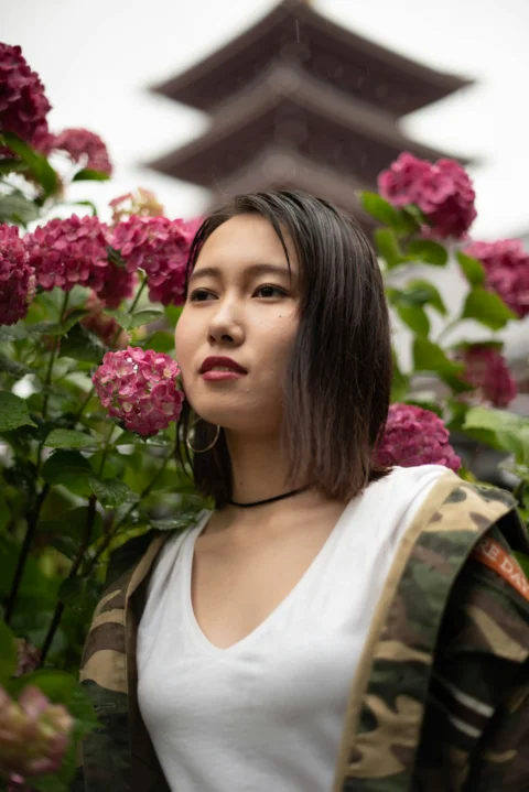 a woman standing in front of pink flowers