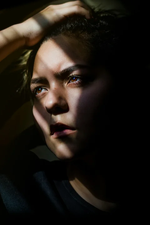 黑暗中一名女子抓著自己的頭髮