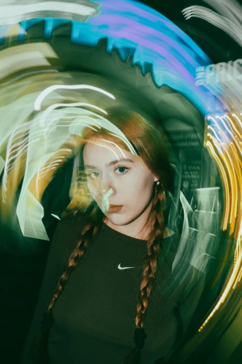 A woman with long braids standing in front of a painting