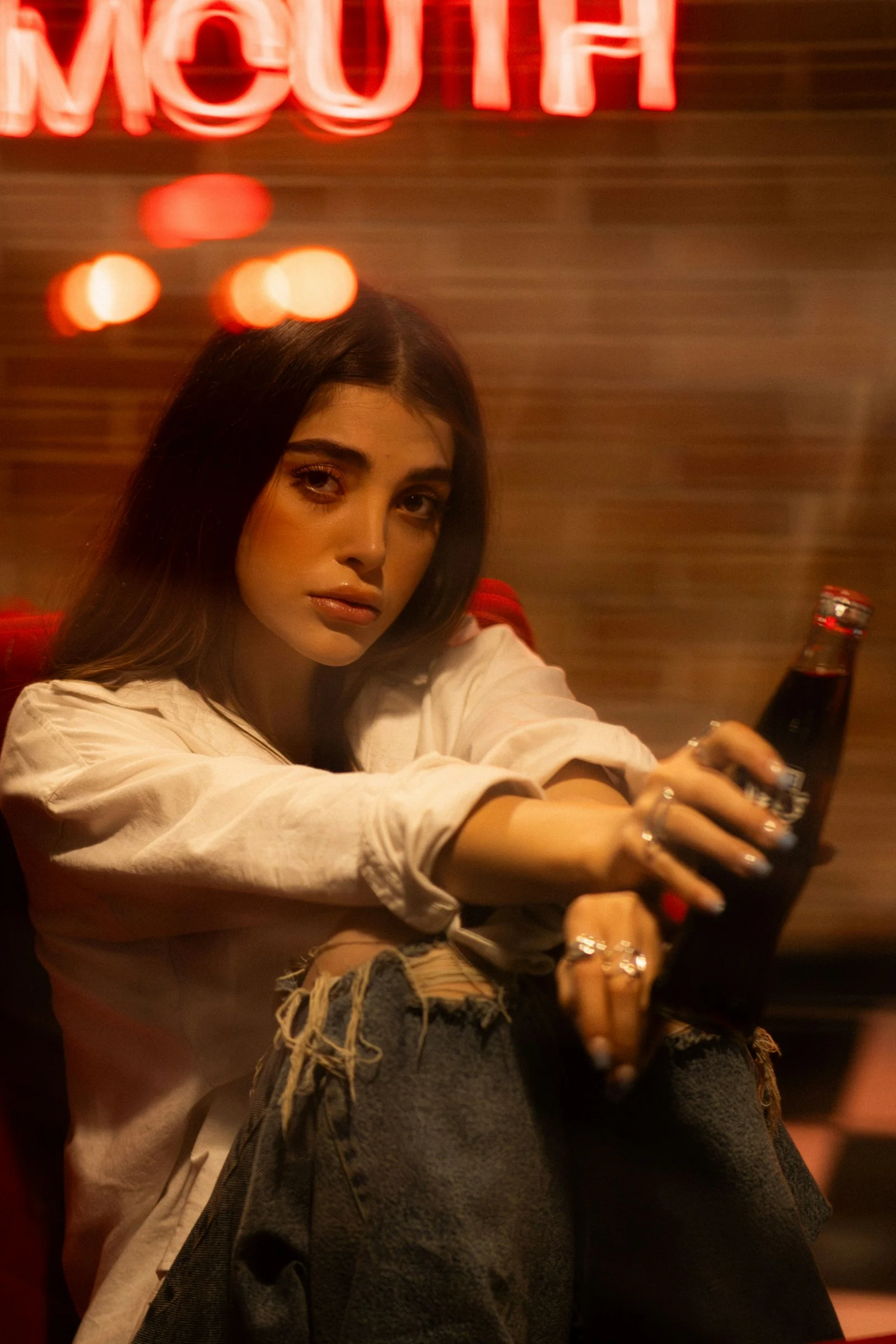 女子拿著酒瓶在酒吧場景中擺姿勢