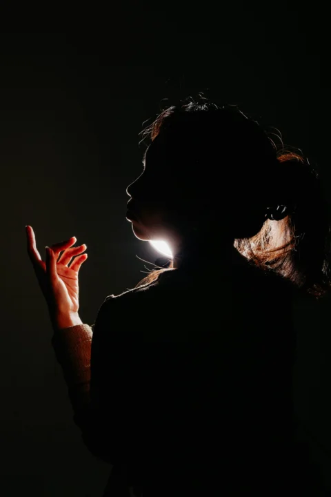 Silhouette of a person with backlighting illuminating hair and hand