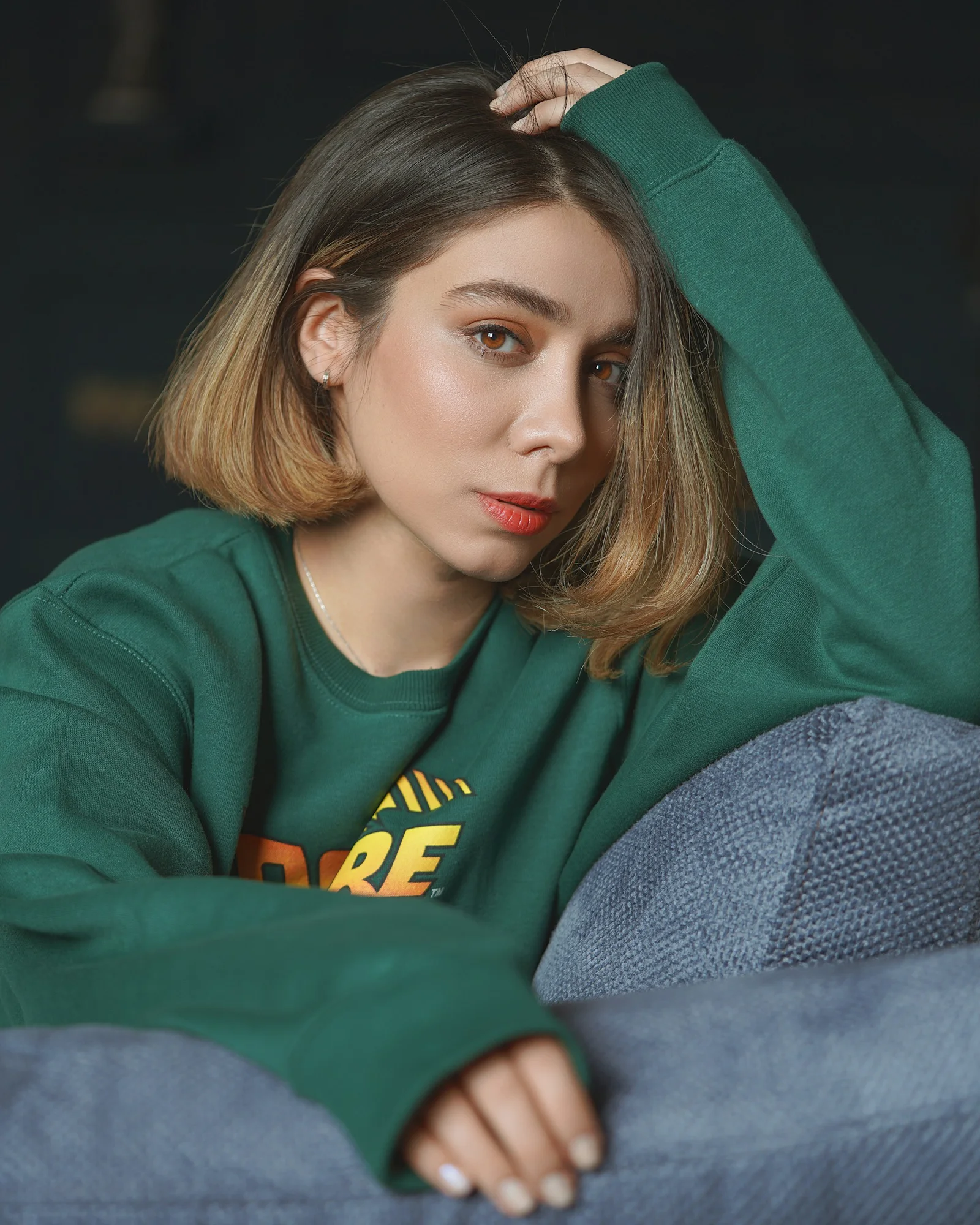 穿綠色長袖襯衫躺在灰色織物上的女性
