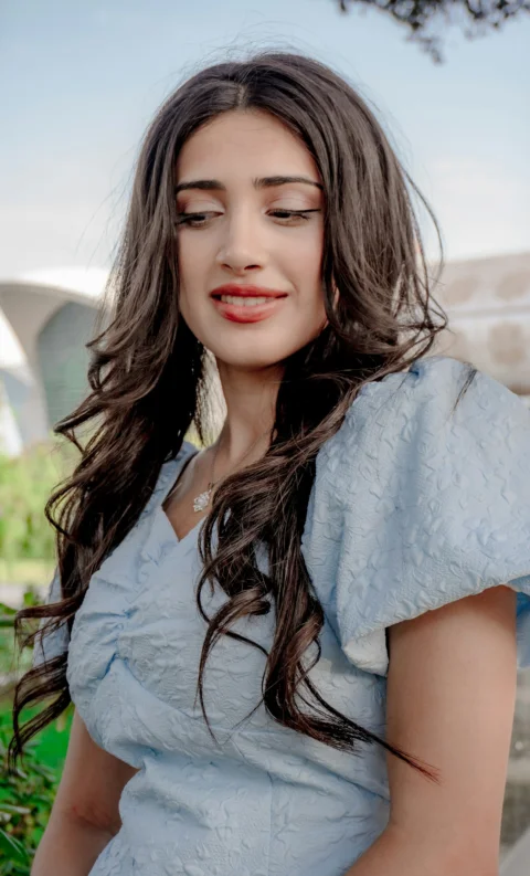 A young woman with long, dark, curly hair smiles