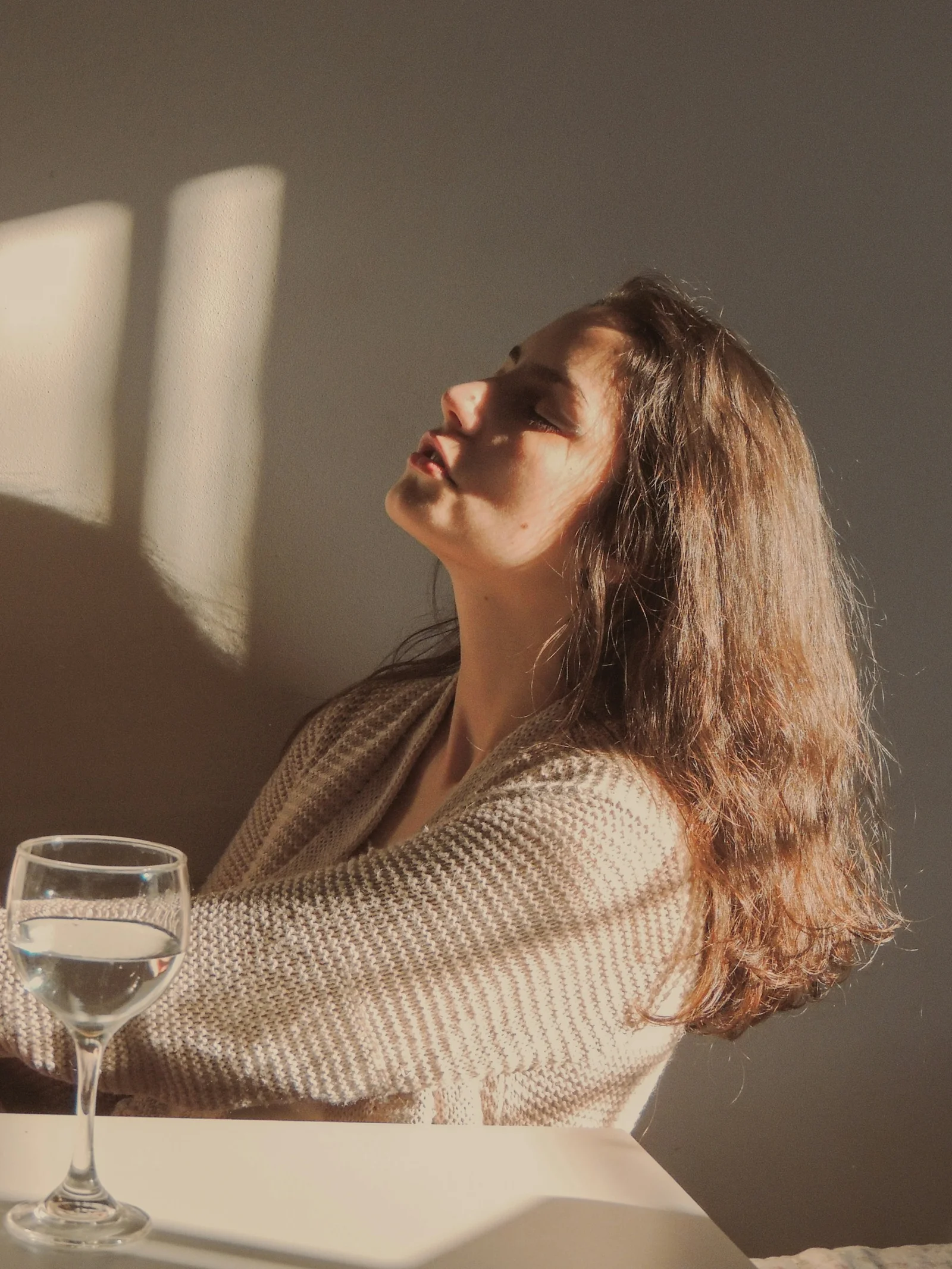 身穿白色针织毛衣的女子手持透明酒杯