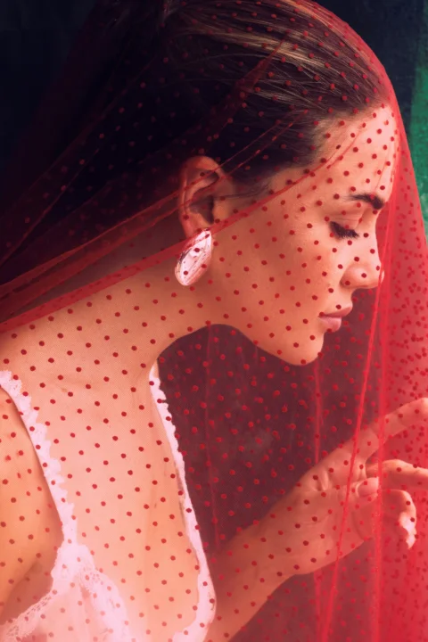 A woman wearing a red veil and holding a cell phone