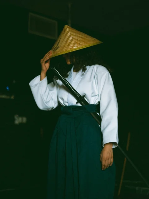 A woman wearing a straw hat and holding a sword