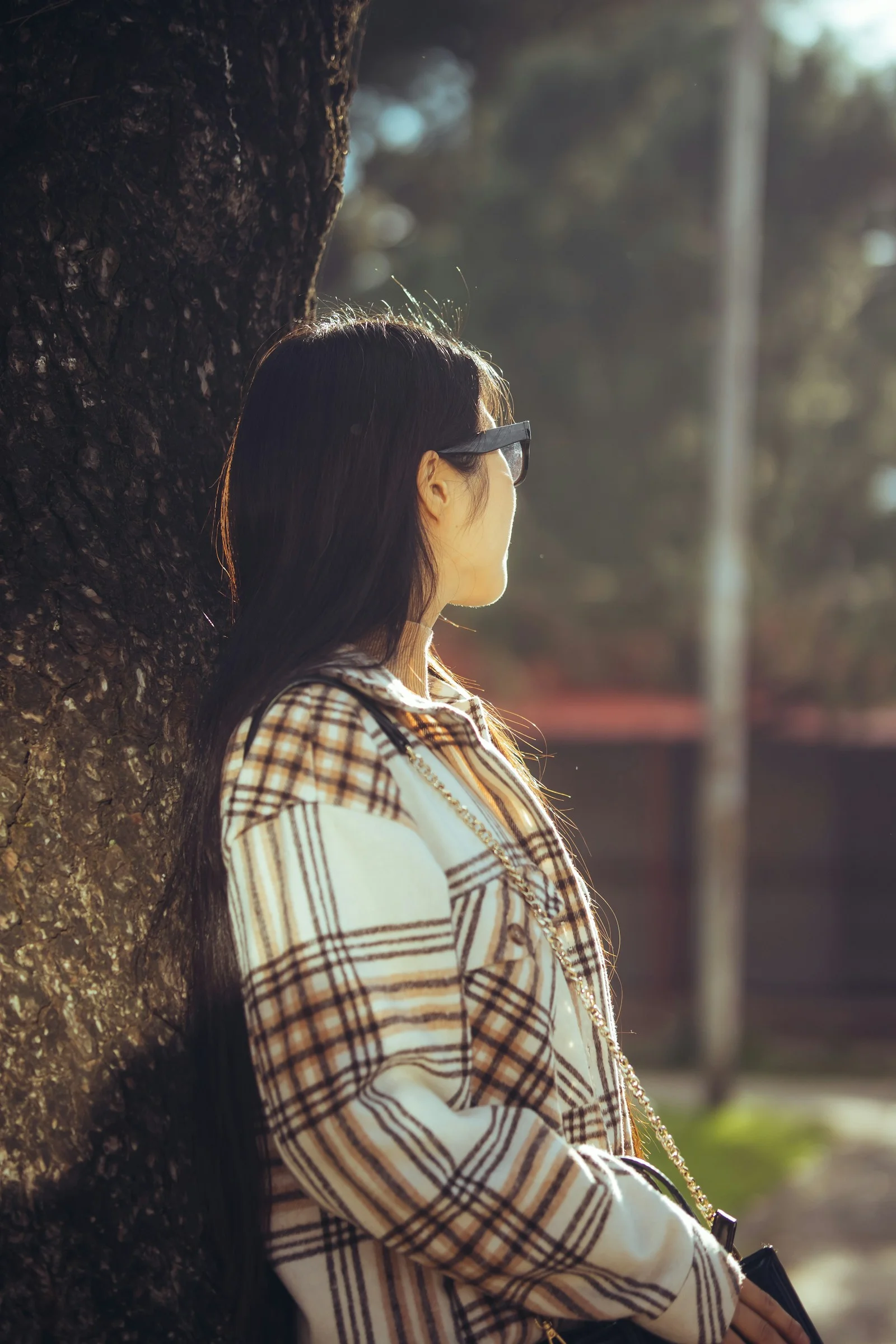 戴太阳镜的女人站在树旁