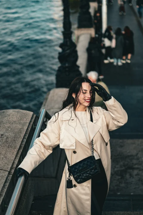 a woman in a trench coat walking down a flight of stairs