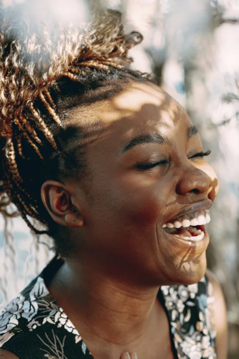 A woman laughs joyfully in the sunlight