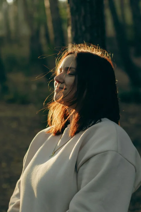 A woman standing in the woods with her face painted