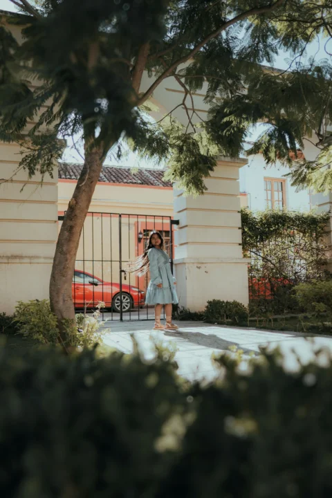 A woman poses outside a beautiful gate
