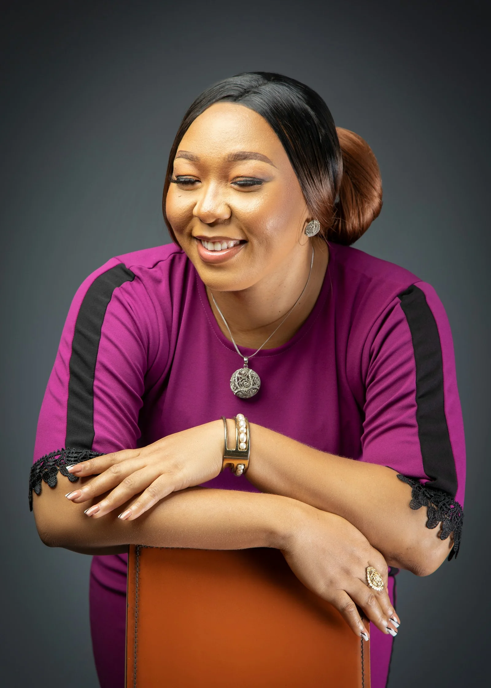 A woman in a purple top with black stripes leaning on a chair