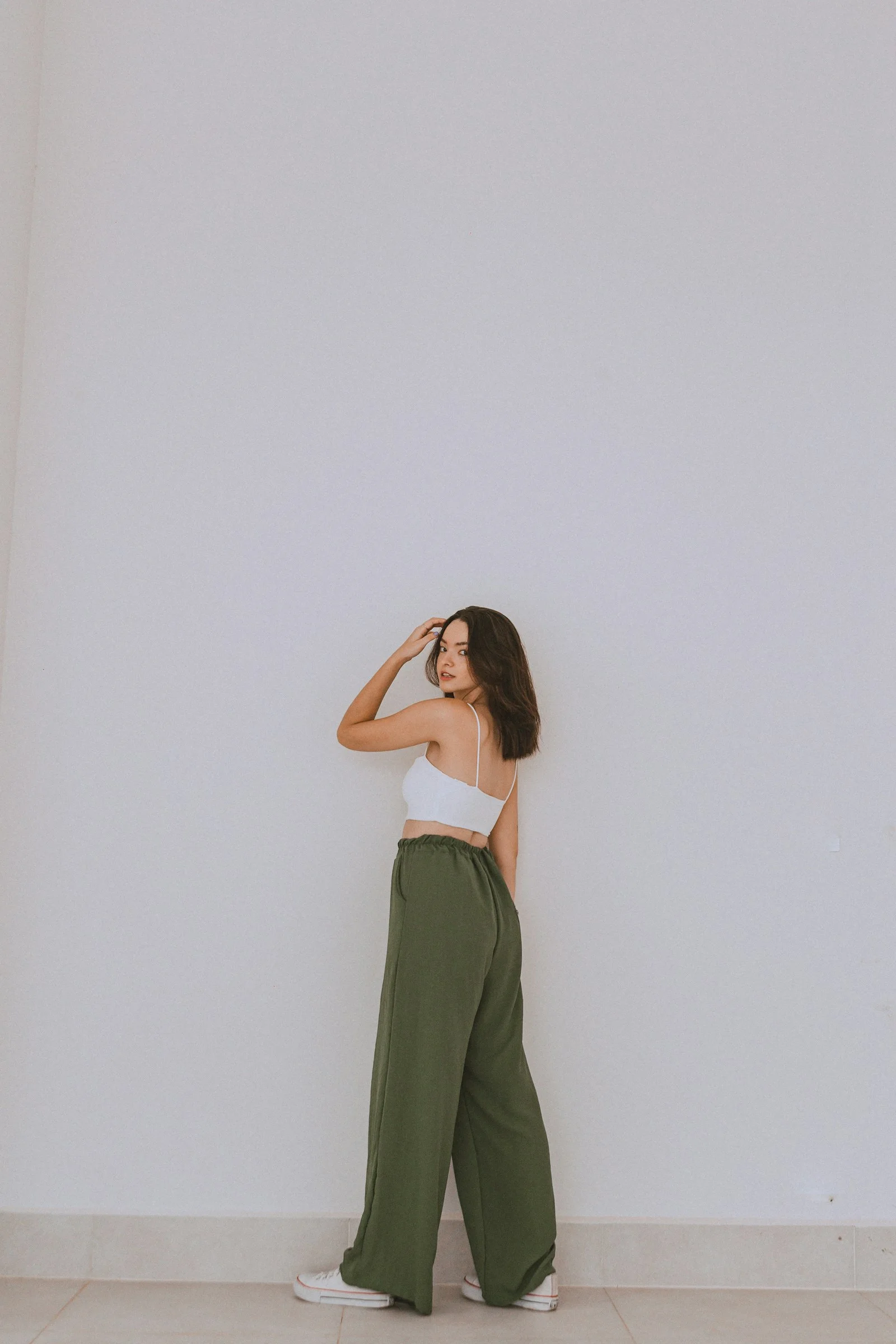 a woman standing against a wall with her hand on her head