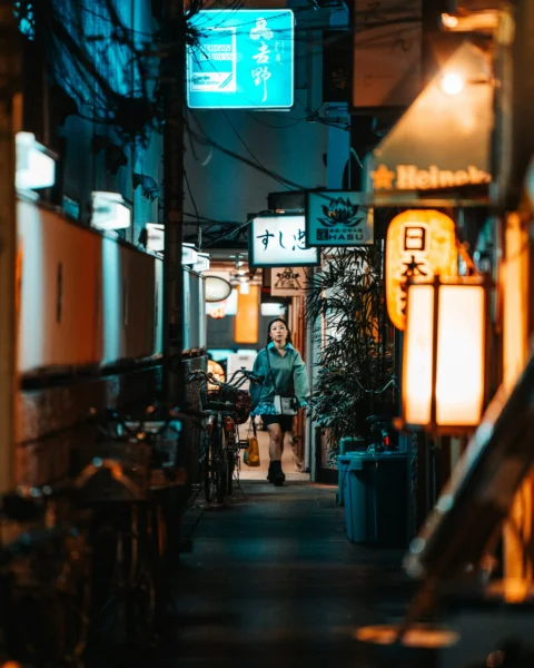 夜晚一个人走在霓虹灯照亮的小巷中