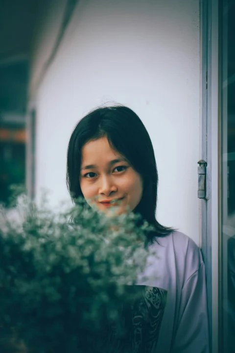 a woman standing next to a bush with a smile on her face