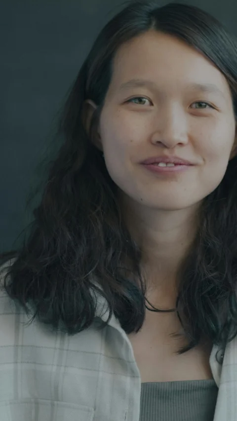 一位留著深色長捲髮、身穿淺色格紋襯衫的女子