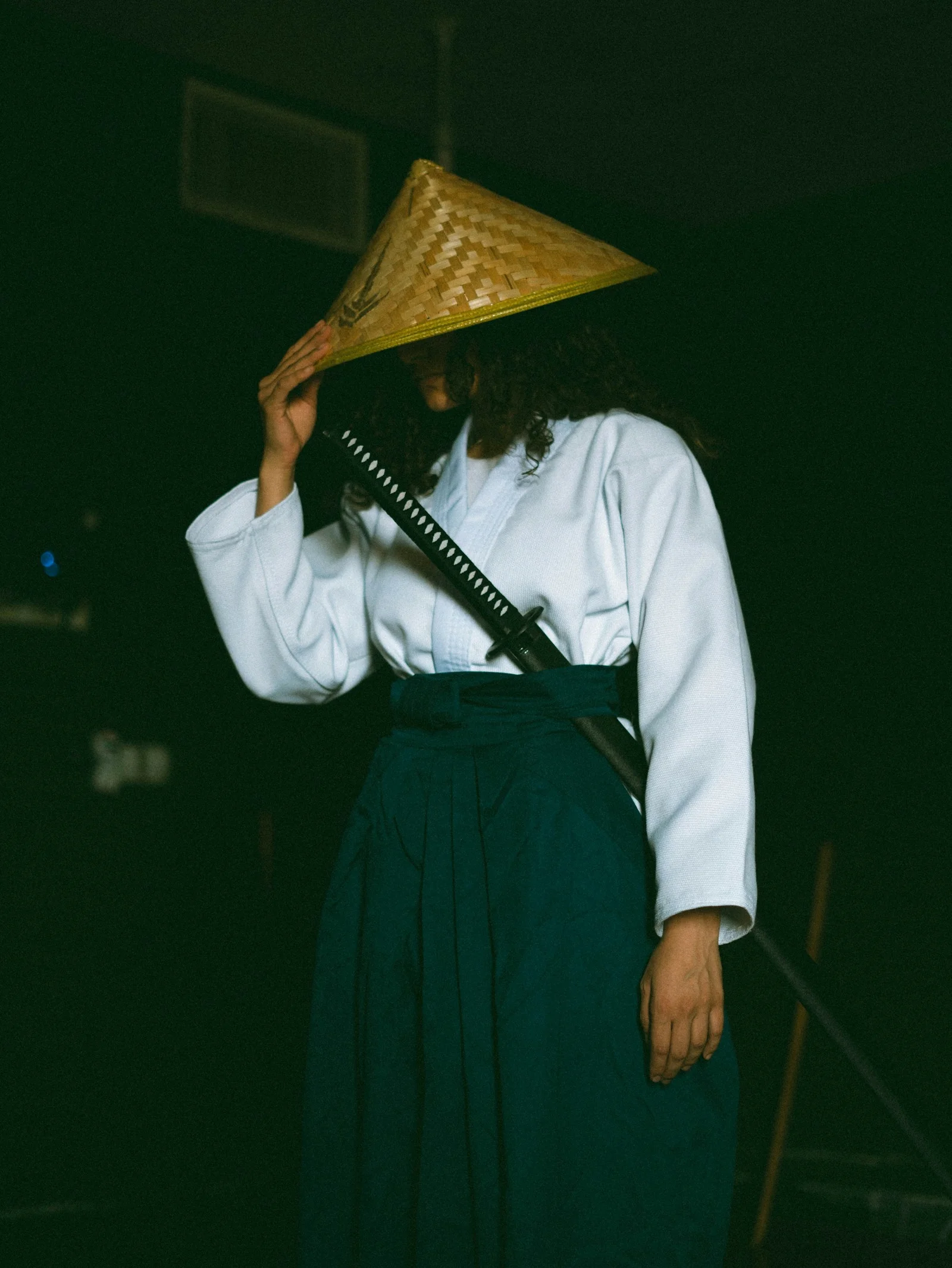 A woman wearing a straw hat and holding a sword